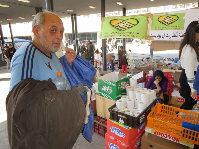 Sottopassaggio Keleti: finalmente è arrivata l'Associazione di assistenza islamica. Questo signore è un barbone ungherese (se ne vedono tanti a Budapest) il quale ha chiesto un rotolo di carta igienica. La responsabile del banco ha respinto la richiesta perchè non è profugo. Evidentemente, la signorina ha ritenuto che un "profugo in patria" non abbia diritto a un rotolo di carta igienica. Così è se vi pare!