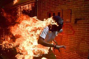 Ragazzo venezuelano avvolto dalle fiamme da cui cerca di scappare